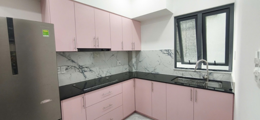 Chi tiết tủ bếp màu hồng với mặt đá đen và kính ốp vân mây